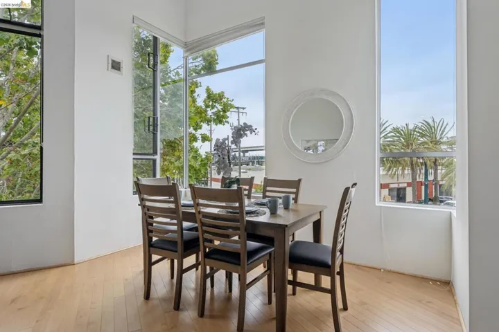 Dining area featuring expansive corner windows, light wood-finish flooring, and white painted walls