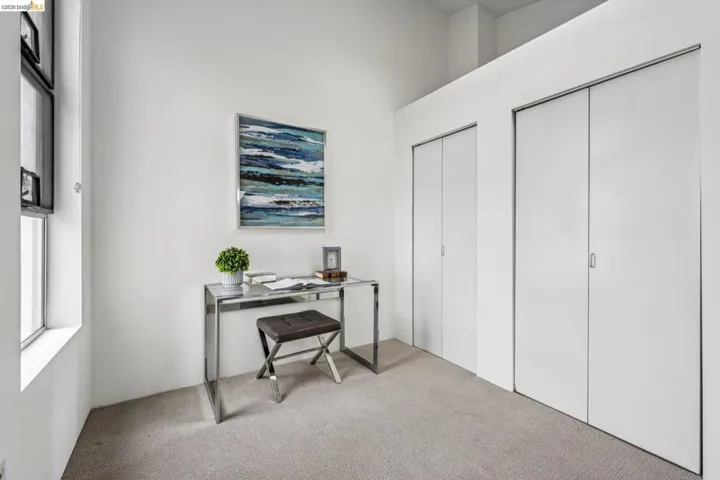 High ceilings define this versatile space featuring light-colored carpeting, multiple windows, and two sets of flush-panel bi-fold doors