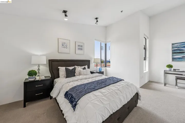 Bedroom featuring high ceilings, light-colored carpeting, white wall finishes, and track lighting