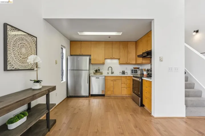 Open-concept kitchen featuring wood cabinetry, stainless steel appliances, and wood-finish flooring