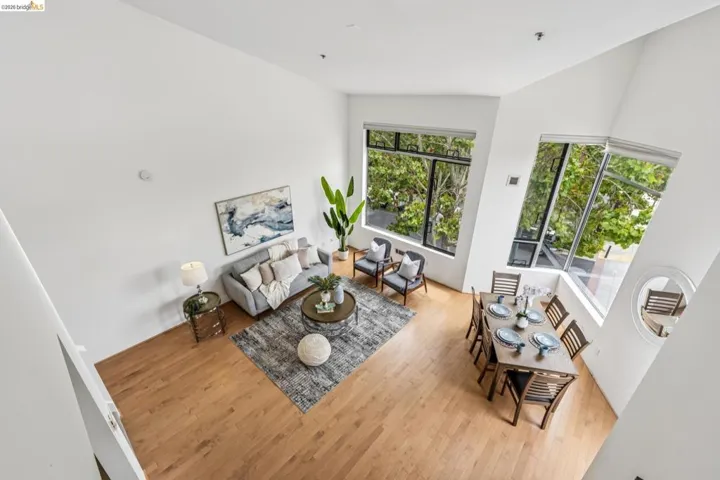 Spacious living area featuring high vaulted ceilings, expansive windows, wood-finish flooring, and a dedicated dining space