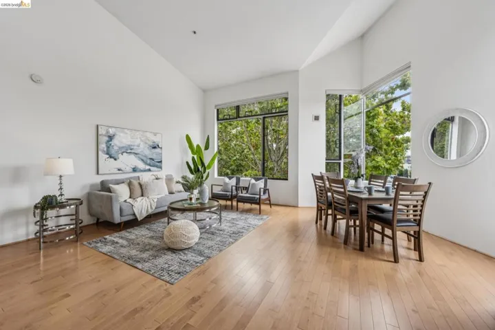 Open-concept living area with light wood-finish flooring, high vaulted ceilings, and extensive window-framing offering natural light