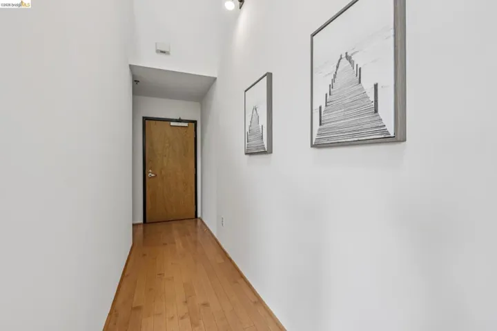 Hallway with wood-finish flooring, white walls, and track lighting