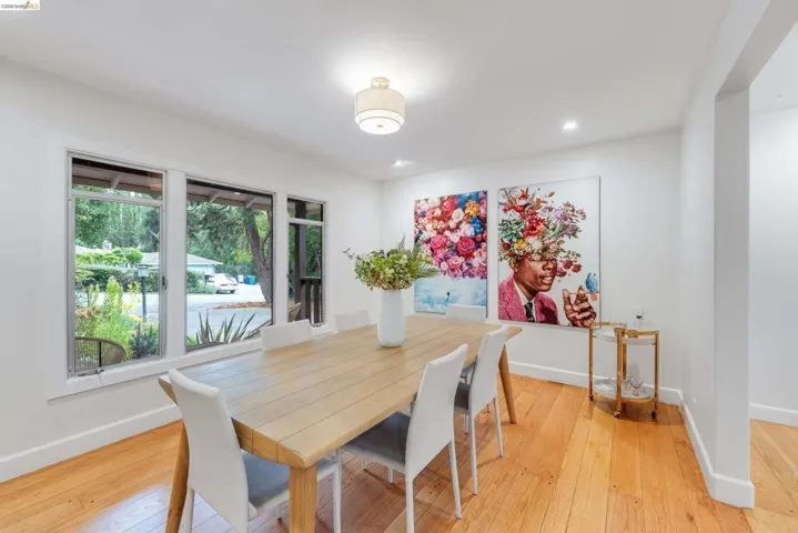 Open dining area featuring wood-finish flooring, white walls, and a series of large windows