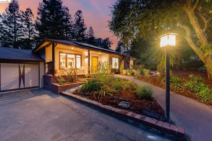 Ranch-style exterior with a covered porch, brick planter beds, a concrete driveway, and a pathway leading to the entry