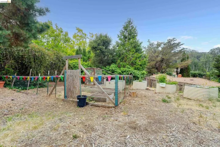 Expansive outdoor space featuring multiple raised garden beds, a fenced garden area, and mature trees providing natural screening