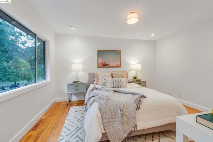 Bedroom featuring wood-finish flooring, recessed lighting, and a window with white trim