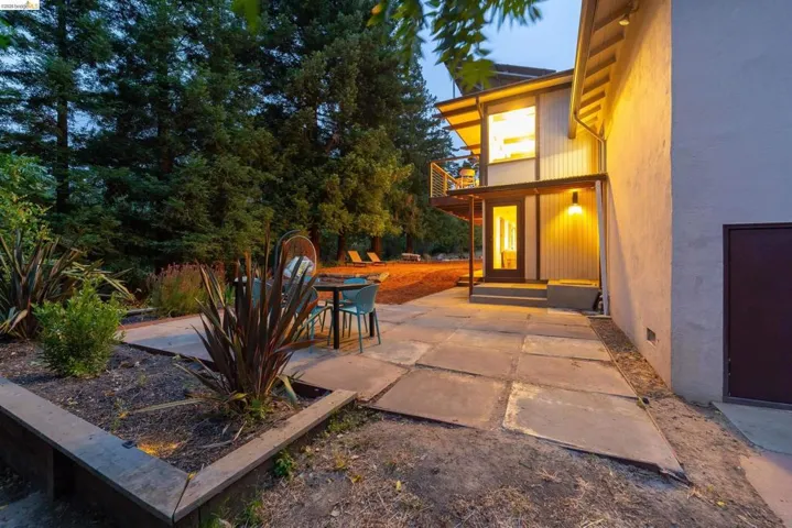 Expansive stone patio with surrounding landscape beds and mature perimeter trees
