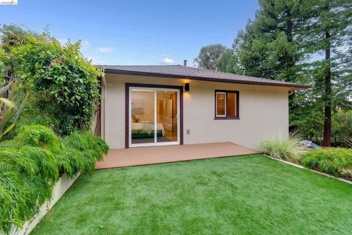 Rear exterior with a composite deck, a sliding glass door, a stucco finish, and a window with dark trim