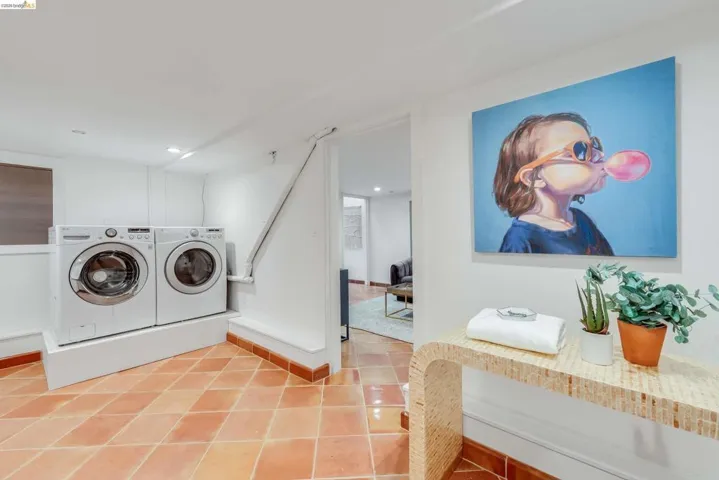 Laundry area featuring terracotta-style floor tiles, white walls, and a built-in platform for appliances