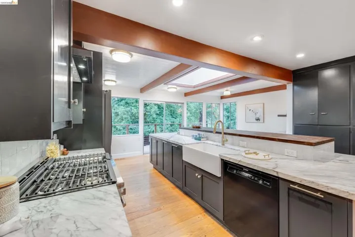 Open-concept kitchen featuring dark cabinetry, marble countertops, and a farmhouse sink