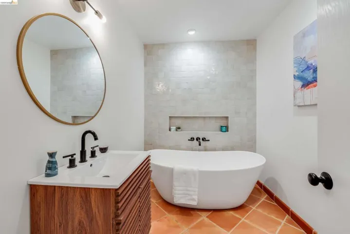 Freestanding soaking tub complemented by wall-mounted fixtures
