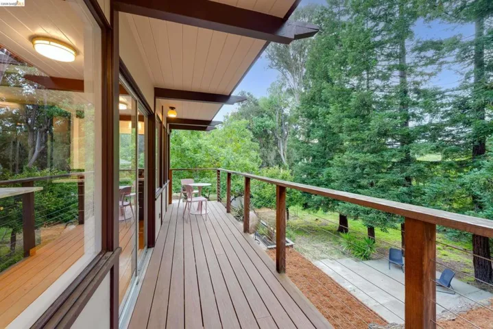 Expansive exterior deck featuring wood-finish decking, cable railing, and a wood-slat ceiling with recessed lighting