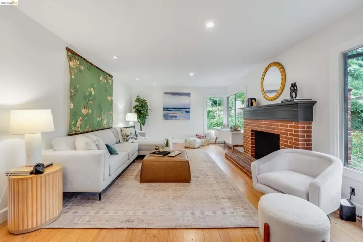 Living area featuring a prominent brick fireplace with a dark mantel, wood-finish flooring, recessed lighting, and large windows