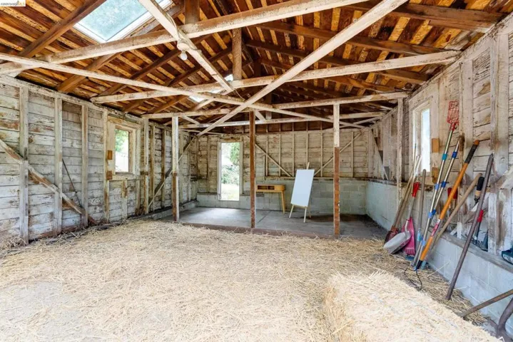 Rustic interior space featuring exposed wooden beams and a skylight