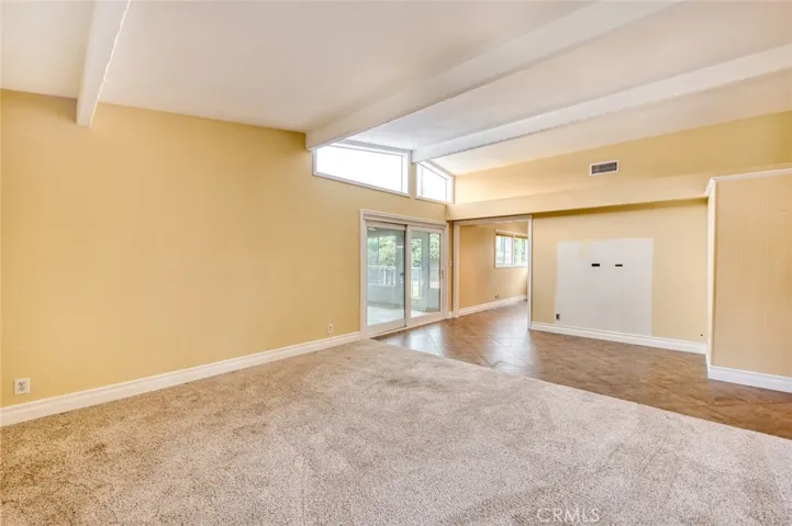 The living room with tall, beamed ceilings flows effortlessly into the formal dining area, and easy access to the versatile sun room, creating an ideal setting for both entertaining and everyday living.