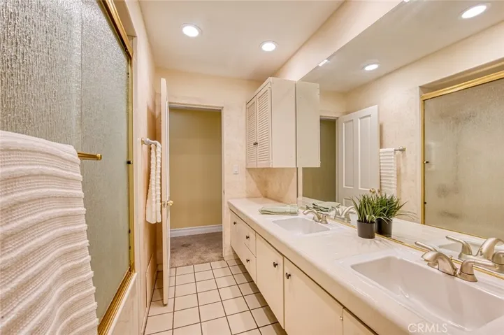 Hall bathroom with tub/shower combo, storage and double sinks.