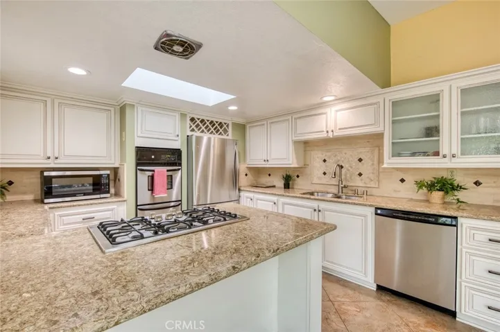 The remodeled kitchen features custom soft-close cabinetry and drawers, generous counter space, and a convenient peninsula with bar seating.