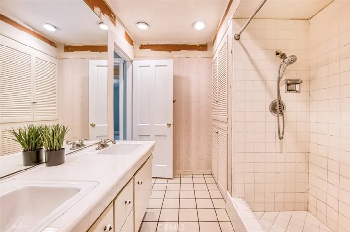 Primary en-suite bathroom with double sinks, linen storage and walk-in shower.