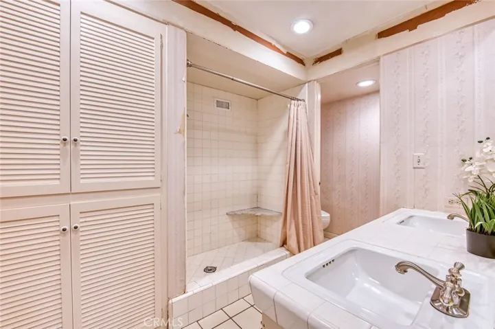 Primary en-suite bathroom with linen storage, walk-in shower and double sinks.