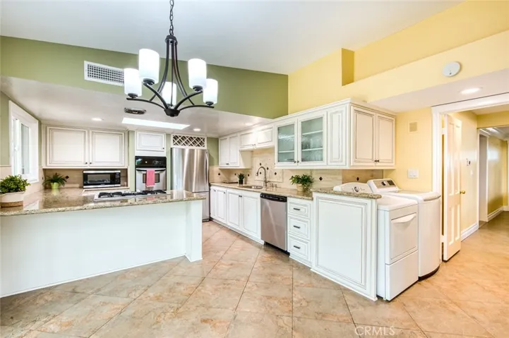 The remodeled kitchen features custom soft-close cabinetry and drawers, generous counter space, a convenient peninsula with bar seating, and an adjoining casual dining area.