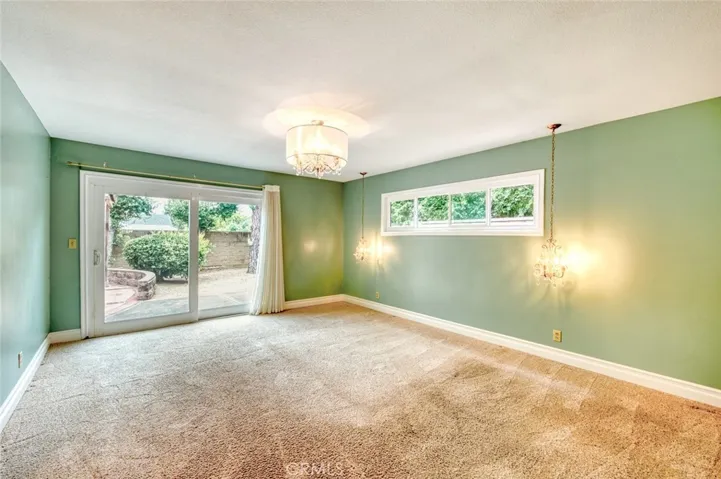 Privately situated, the expansive primary suite provides a relaxing sanctuary and a sliding glass door offering direct access to the backyard—perfect for enjoying your morning coffee or unwinding beneath the evening sky.