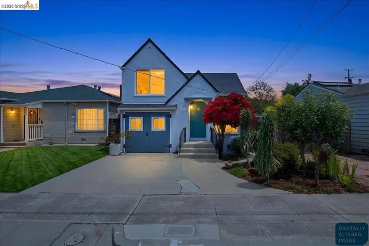 Two-story light-toned residence featuring a prominent gable roofline and a dark teal front door