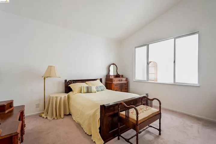 Spacious room featuring a vaulted ceiling and a large window with three panes