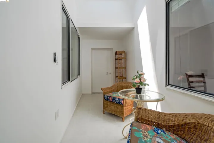 Bright interior corridor featuring multiple windows, a white door, and light-toned flooring