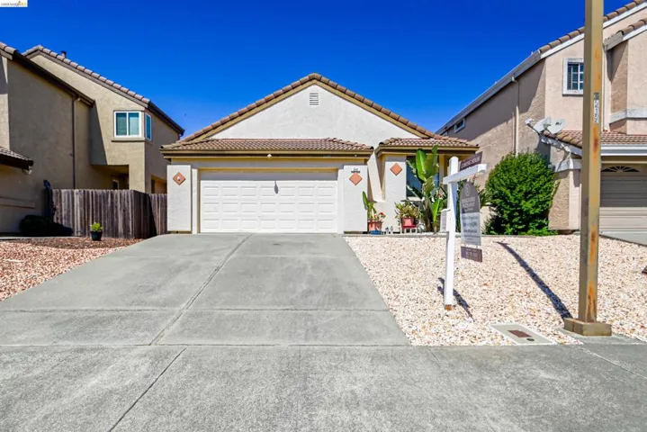 Single-story residence featuring a tile roof, an integrated two-car garage, and a concrete driveway
