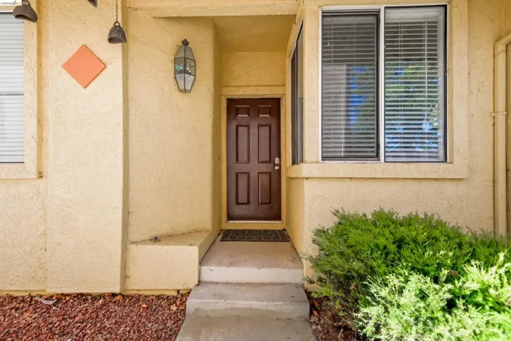 Entryway featuring a paneled door, decorative exterior lantern, concrete steps, and a bay window