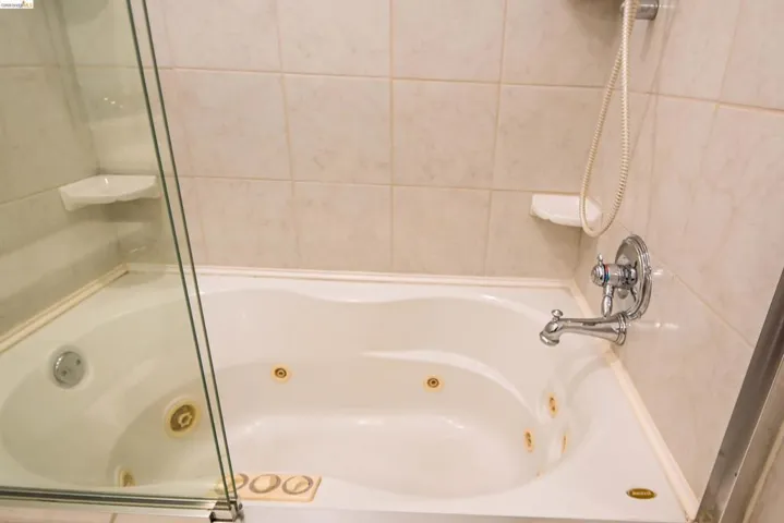 Jetted tub with chrome fixtures and light-toned tile surround