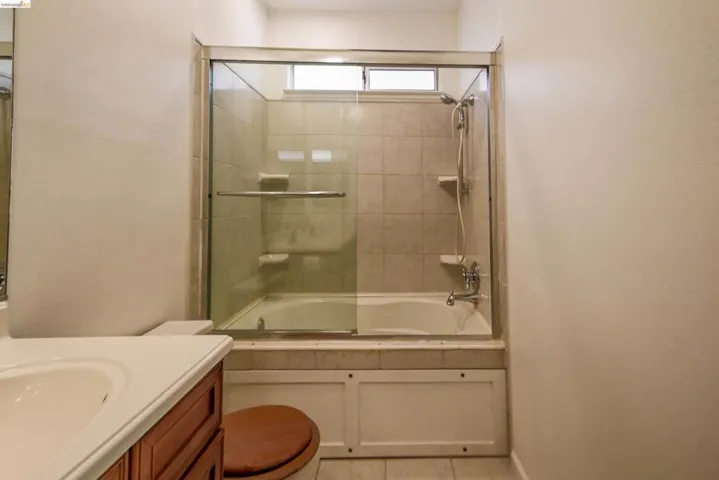 Bathroom featuring a tub/shower combination with tile surround and glass enclosure