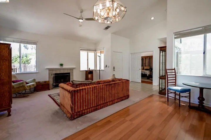 Spacious living area featuring vaulted ceilings, a central fireplace with a tile surround, and multiple large windows