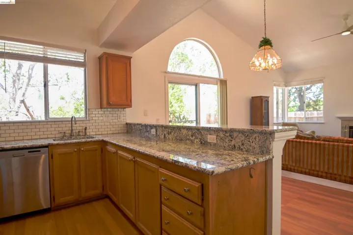 Kitchen featuring granite countertops, a subway tile backsplash, and light wood cabinetry
