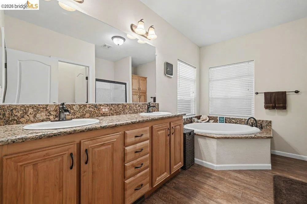 Full bath featuring double vanity, a bath, dark wood finished floors, and a shower stall Full bath featuring double vanity, a bath, dark wood finished floors, and a shower stall