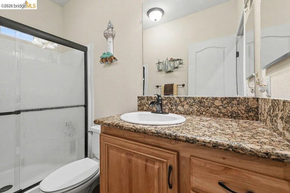 Bathroom featuring vanity, a shower stall, and a textured wall Bathroom featuring vanity, a shower stall, and a textured wall