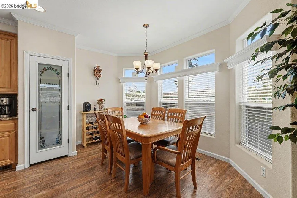 Dining room featuring ornamental molding, dark wood-type flooring, and suspended lighting Dining room featuring ornamental molding, dark wood-type flooring, and suspended lighting