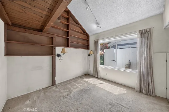 Downstairs bedroom with built-in bookshelves and large window.