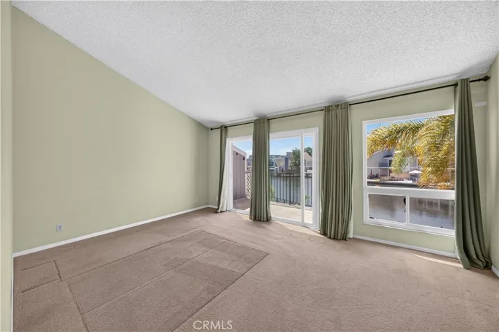 Primary suite with vaulted ceilings and wall of windows/doors offers great water views from bed.