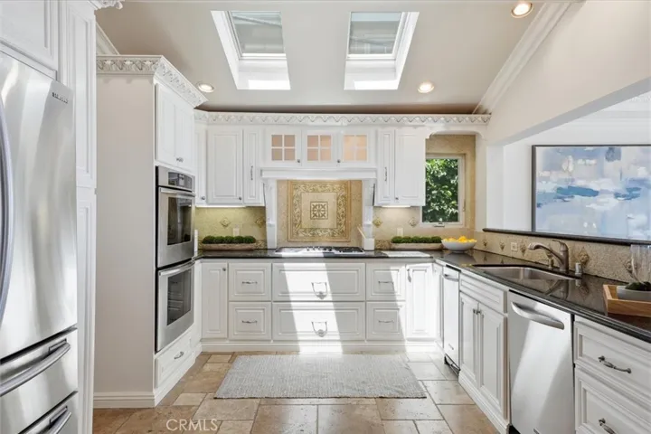Thermador double oven and cooktop and custom mosaic tile backsplash, spice roll outs to left and right of vent hood.