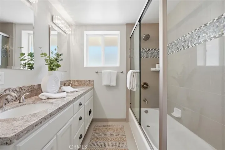 remodeled guest bathroom with dual sinks and pretty tile in shower