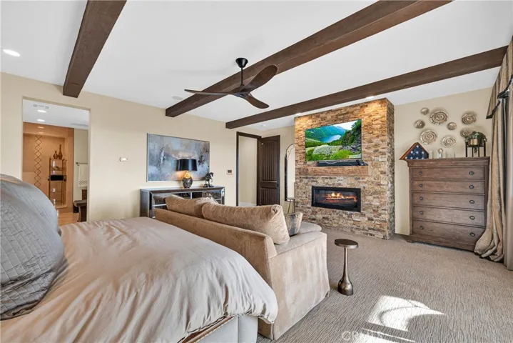 Primary suite with fireplace, beamed ceiling, and balcony access
