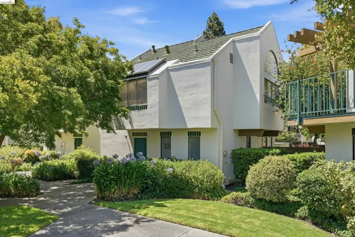Contemporary stucco exterior featuring a green tiled roof and solar panels