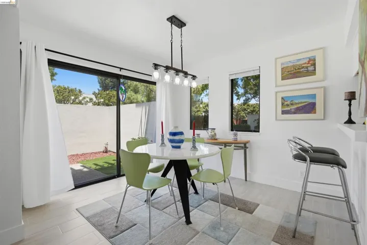 Dining area featuring light wood-finish flooring, a contemporary linear chandelier, and a built-in shelving unit