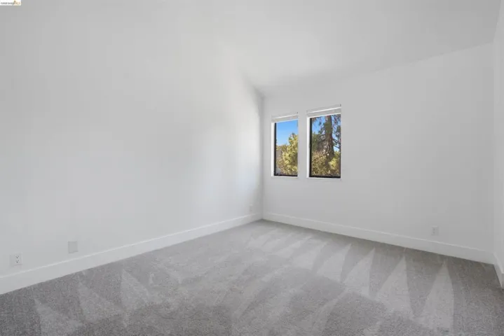 Spacious room featuring neutral carpeting, white baseboards, and bright white walls