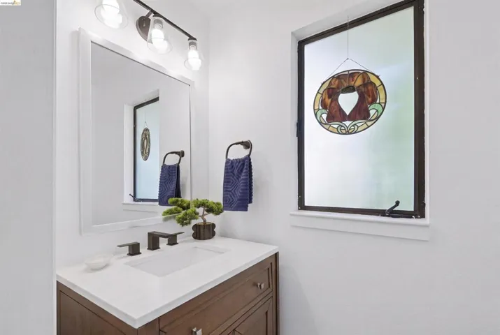 Bathroom vanity with a white rectangular undermount sink, a dark bronze widespread faucet, and a light-toned countertop