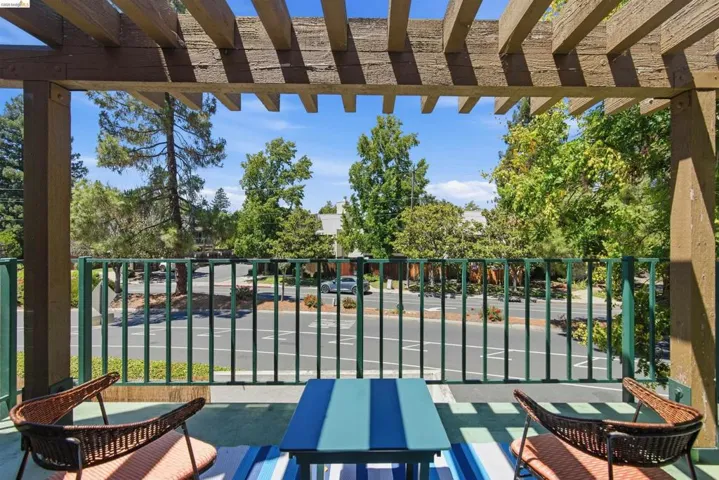 Covered outdoor balcony featuring a wood pergola and green metal railing