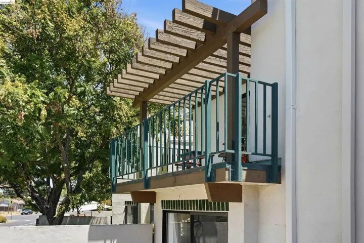 Exterior balcony featuring a wood pergola and teal metal railings