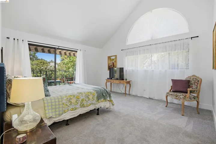 Vaulted white ceilings featuring an arched window with privacy blinds